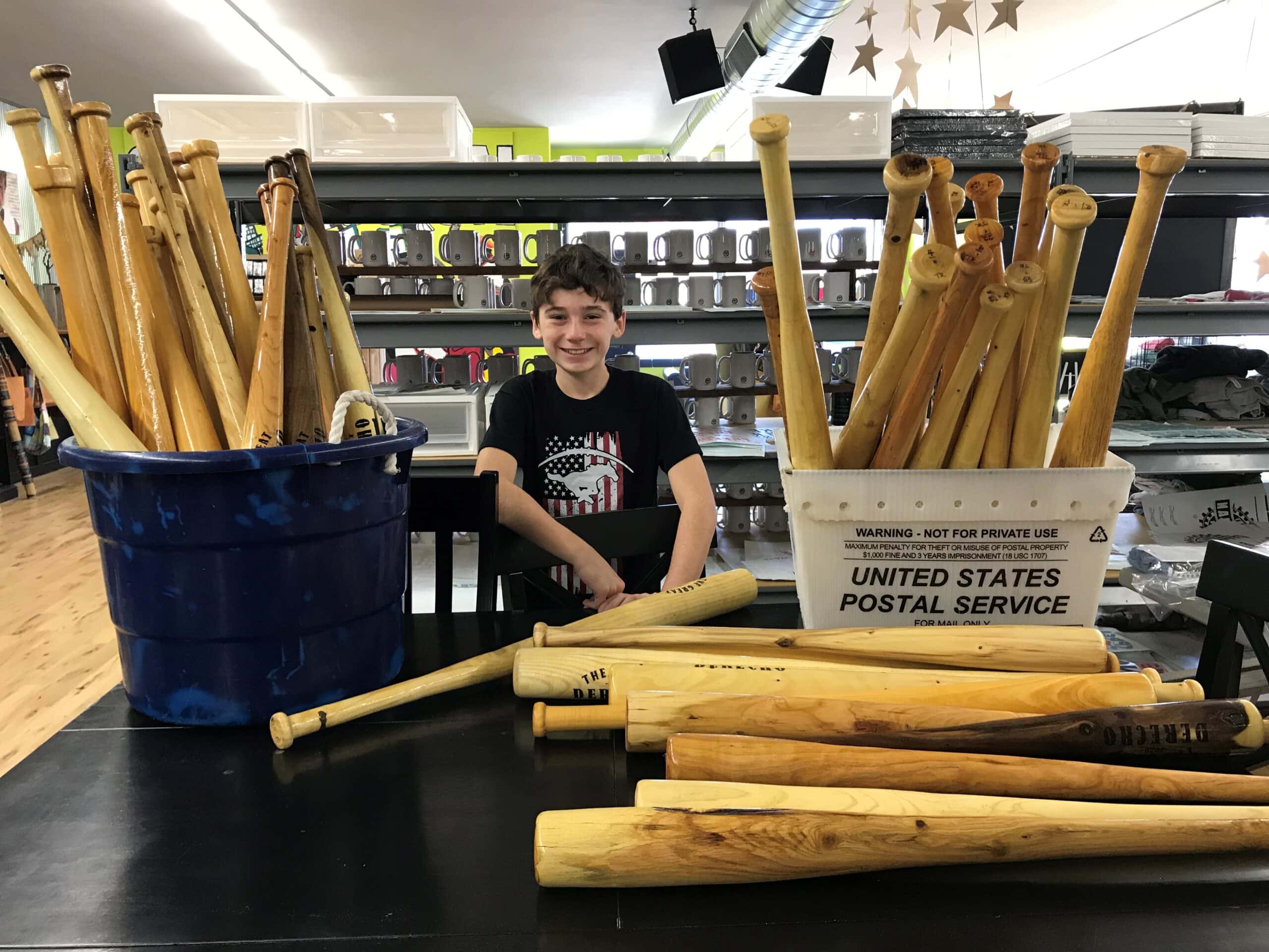 Photo of Tommy Rhomberg posing with baseball bats he made.
