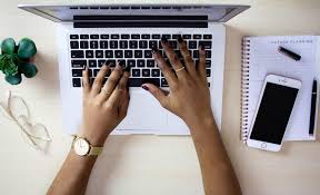Overhead photo of hands typing on a computer.