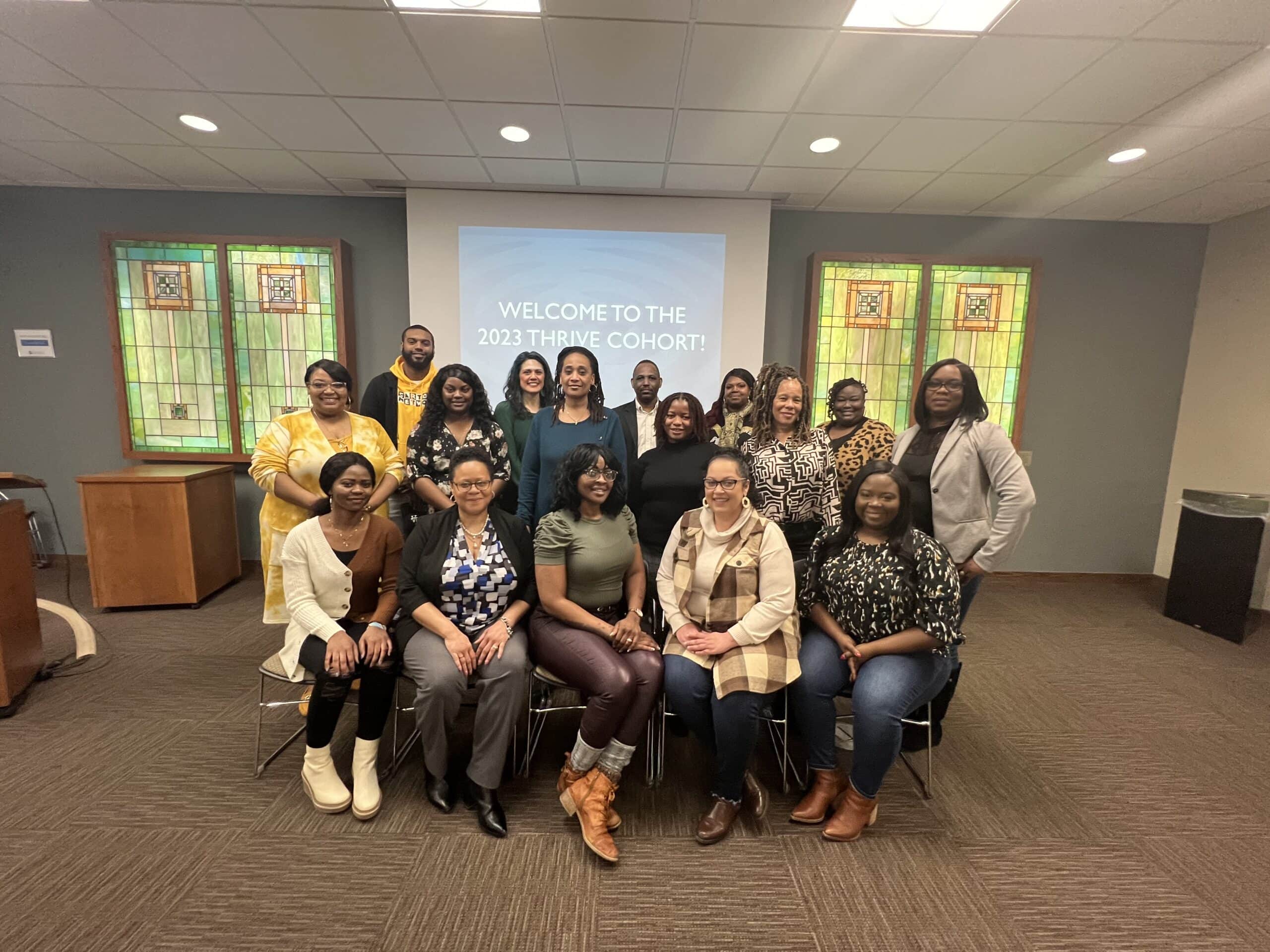 Thrive Cohort participants pose for a group photo in a conference room with stained glass windows.